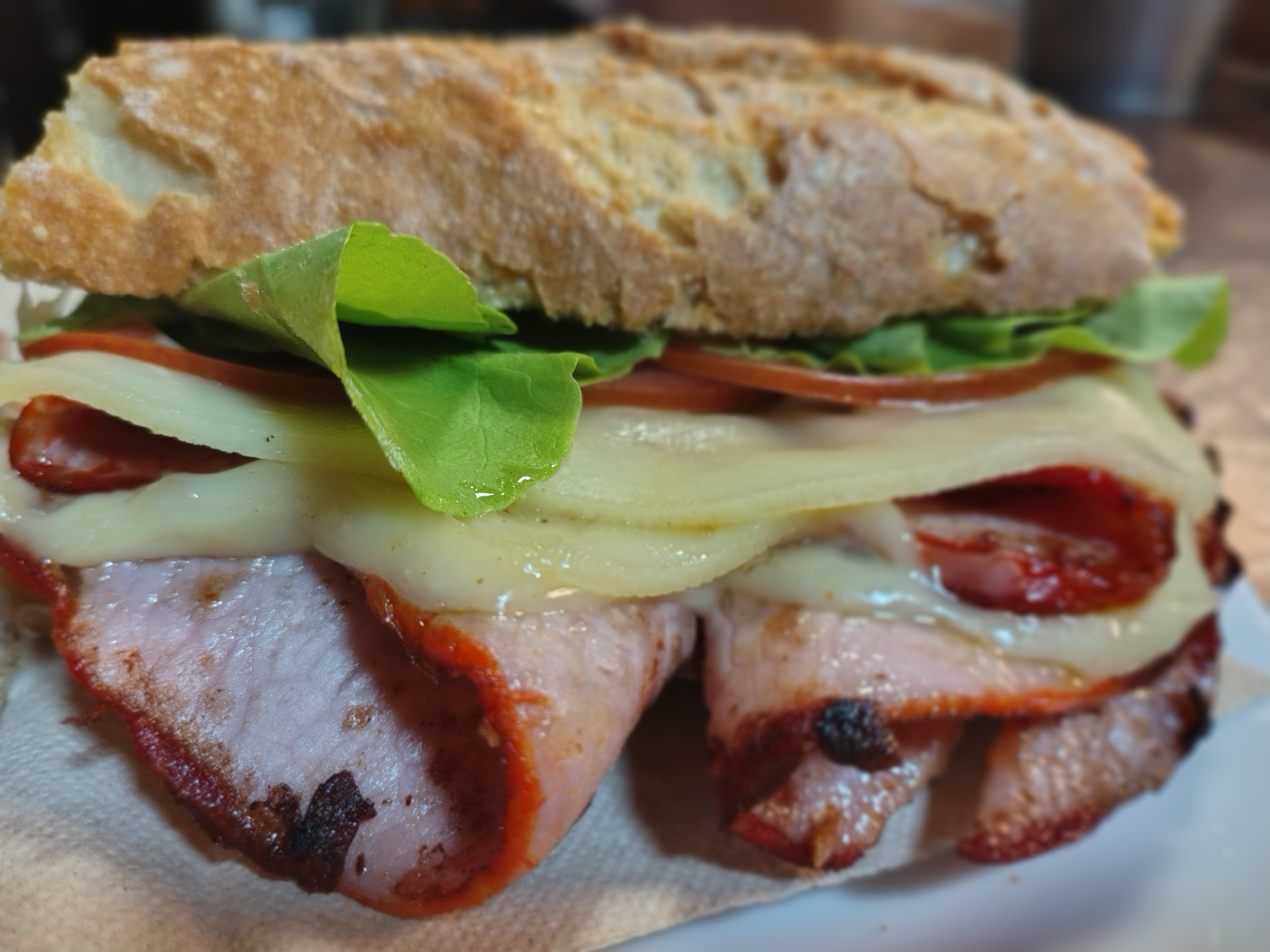 Bocata de lomo adobado con queso fundido, lechuga y tomate en pan de pueblo